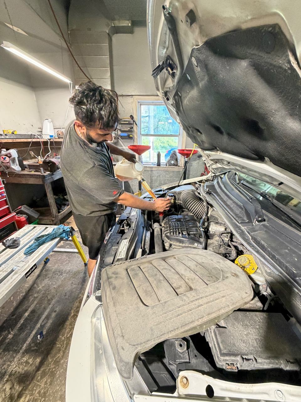ABF technician performing an oil change under the hood of a vehicle